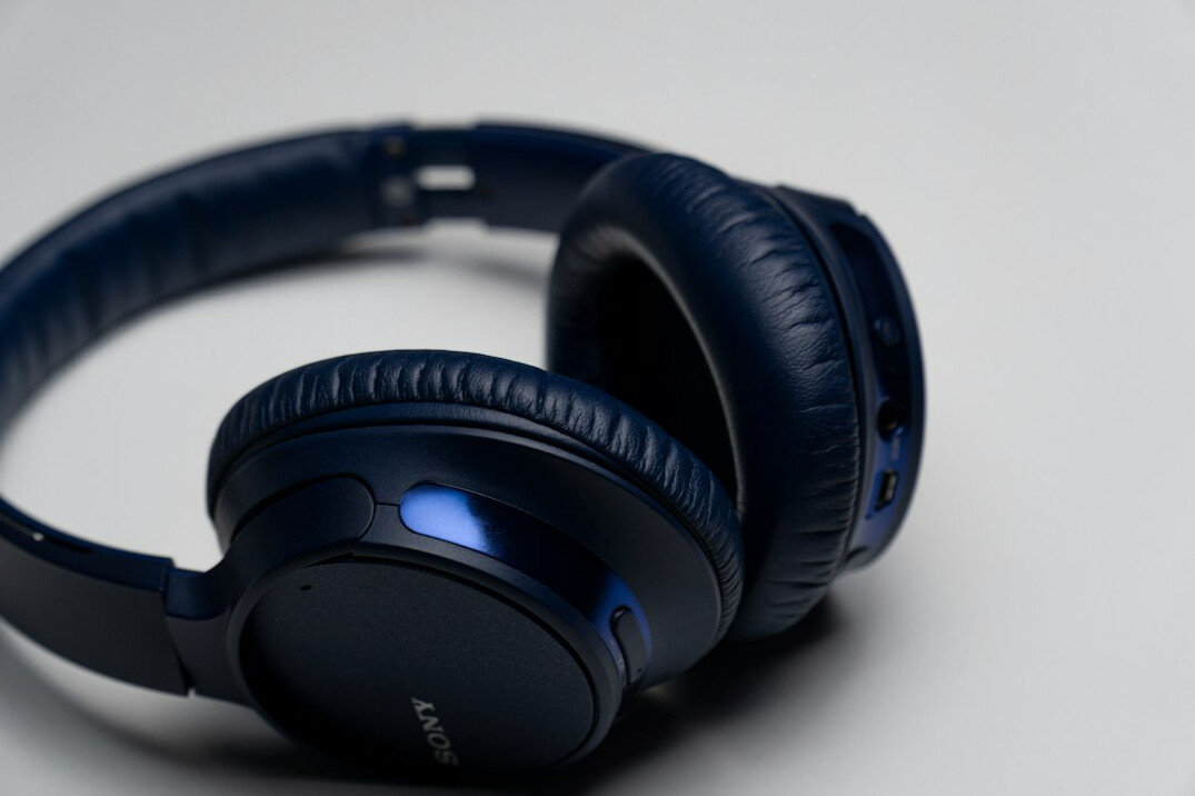 Pair of headphones resting on a wooden desk next to a notebook